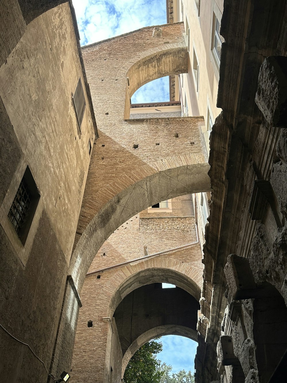Un callejón estrecho con arcos y una torre del reloj al fondo