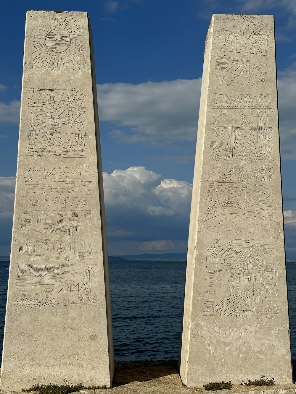 two obelisk standing in front of a body of water