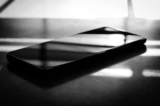 A sleek modern smartphone resting on a minimalist white surface with soft natural lighting