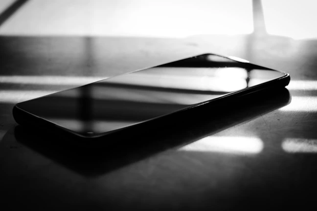 Elegant smartphone resting on a smooth surface with soft shadows.