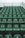 Rows of green stadium seats are arranged in ascending order. Each seat is numbered in white, and the numbers appear to be worn. The seating is on a grey concrete structure, and a metal railing is visible at the top.