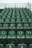 Rows of green stadium seats are arranged in ascending order. Each seat is numbered in white, and the numbers appear to be worn. The seating is on a grey concrete structure, and a metal railing is visible at the top.