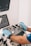 A person wearing blue gloves is operating an ultrasound machine. The control panel is visible with various buttons and dials, and two screens display information. There is also a small bottle in a holder next to the machine.