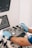 A person wearing blue gloves is operating an ultrasound machine. The control panel is visible with various buttons and dials, and two screens display information. There is also a small bottle in a holder next to the machine.