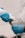A person wearing blue gloves is applying a gel from a bottle onto a medical device, possibly an ultrasound probe, indicating preparation for a medical procedure.