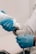 A person wearing blue gloves is applying a gel from a bottle onto a medical device, possibly an ultrasound probe, indicating preparation for a medical procedure.