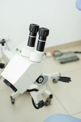 A sleek, futuristic microscope device glowing softly with blue and green accents in a pristine lab setting.