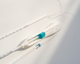 A light-colored medical or scientific instrument with a label stating 'NOT FOR USE IN HUMANS' is positioned horizontally. Thin black wires or threads are also present. The background is plain and neutral, suggesting a clinical or sterile environment.