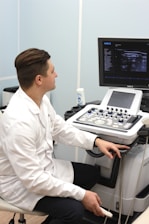 a man in a white lab coat sitting in front of a computer