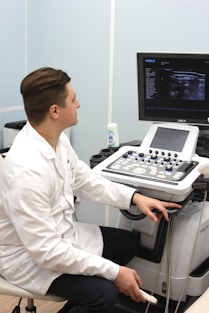 a man in a white lab coat sitting in front of a computer