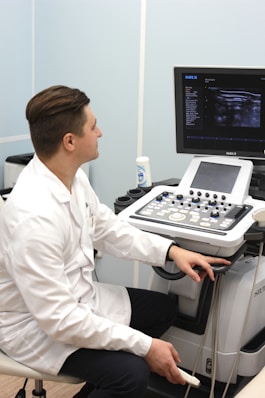 a man in a white lab coat sitting in front of a computer