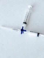 Close-up of medical gloves and syringes arranged neatly on a white surface
