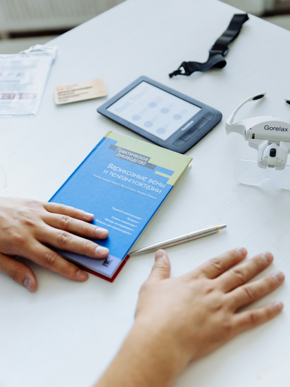 a person holding a book near a remote control