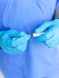 a person in a blue shirt and blue gloves is holding a sy