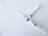 Two syringes intersect at right angles on a white textured surface. Each syringe has clear measurements visible and features a blue valve at the intersection point.