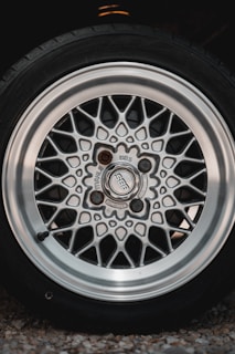 Close-up view of an alloy wheel from a car. The wheel features a detailed mesh pattern with a shiny metallic surface. The brand name 'BBS' is visible at the center, surrounded by lug nuts.
