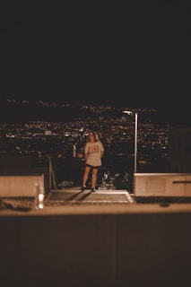 A vibrant cityscape at dusk with a person wearing Lumina Apparel standing on a rooftop.