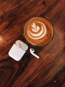 Wireless headphones resting on a minimalist table next to a coffee cup