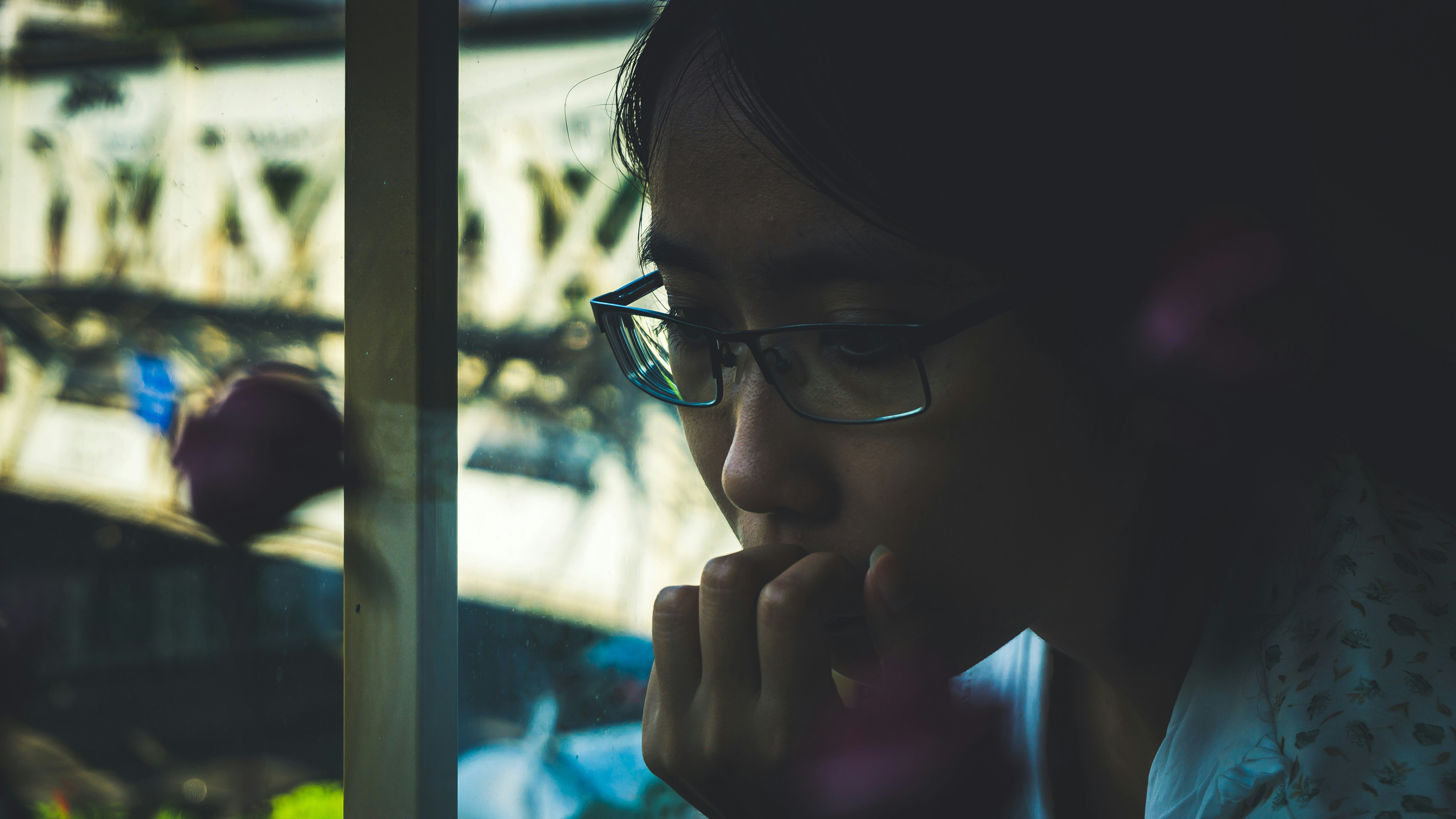 a woman wearing glasses looking out a window