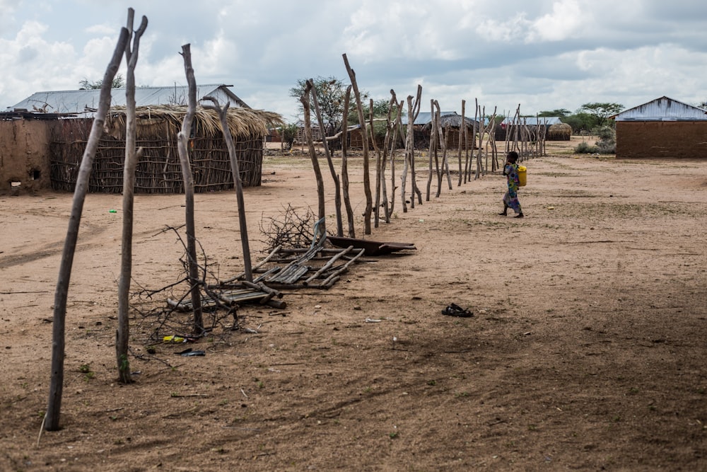 a small child standing in a dirt field next to a fence