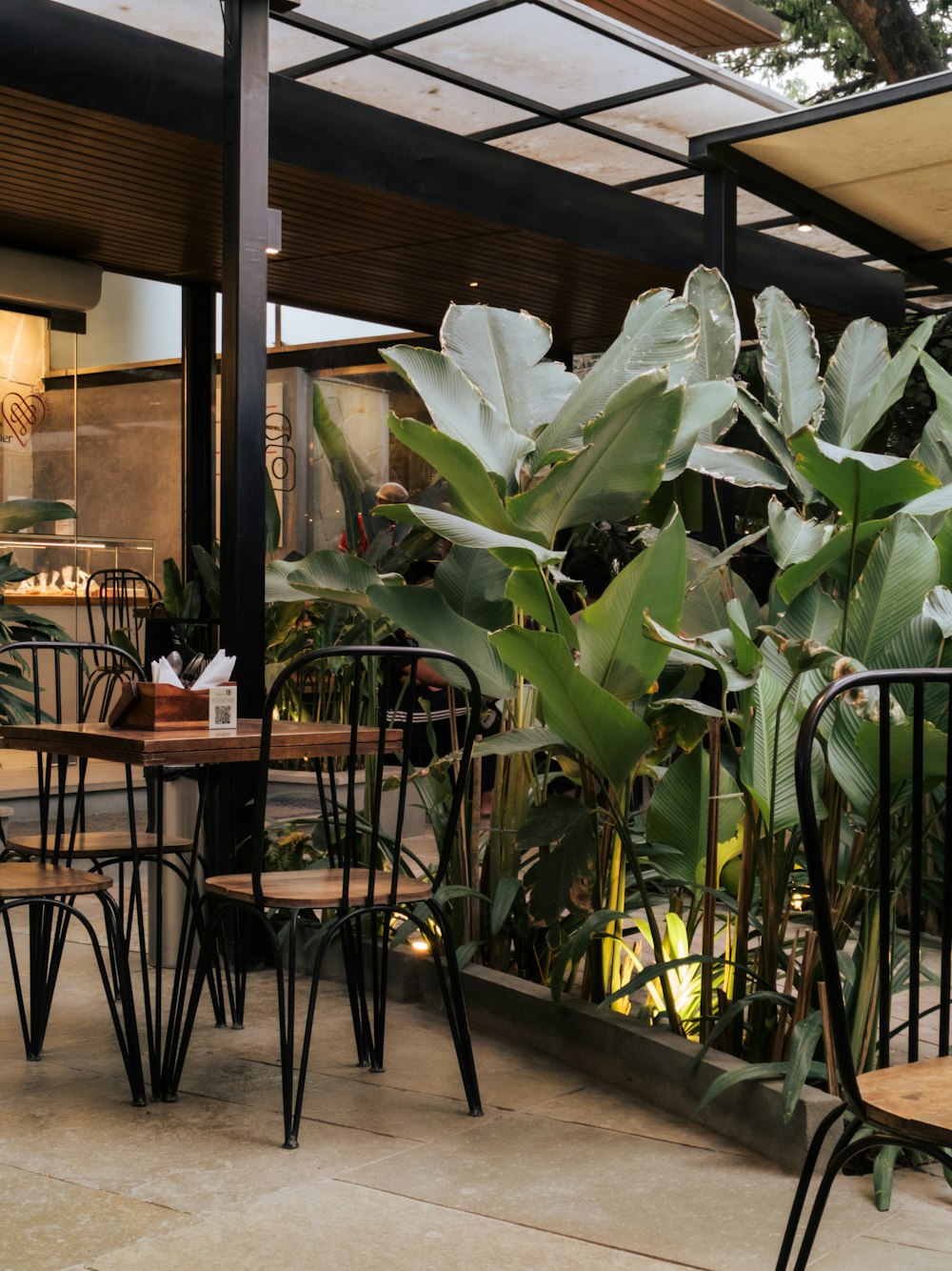 a patio area with tables, chairs and a plant