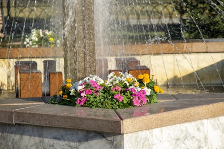 Close-up of a modern water feature surrounded by vibrant flowers and manicured shrubs.