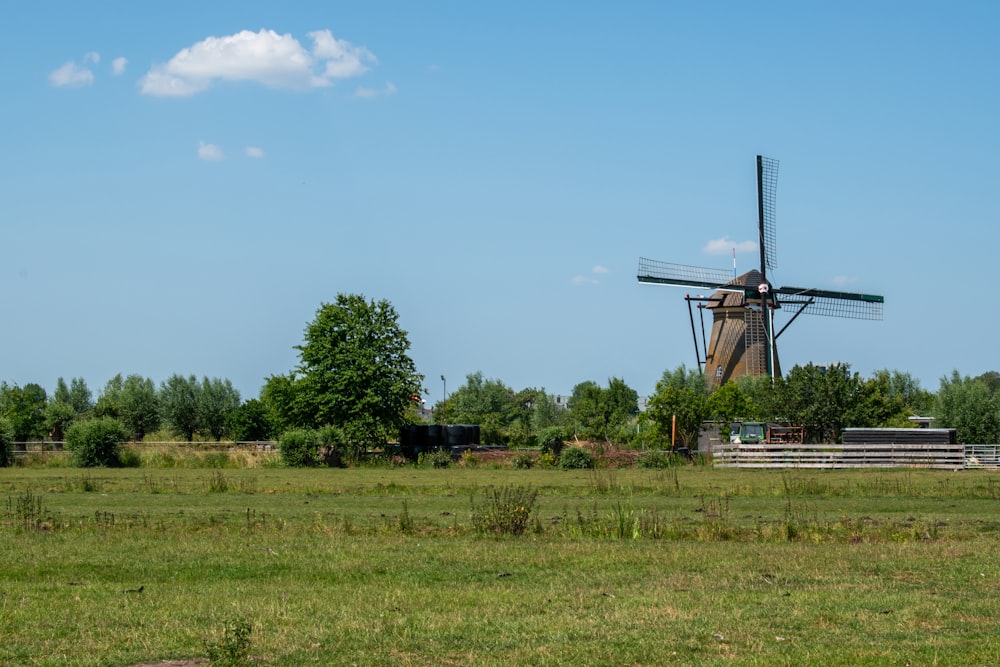 a windmill in a field with trees in the background