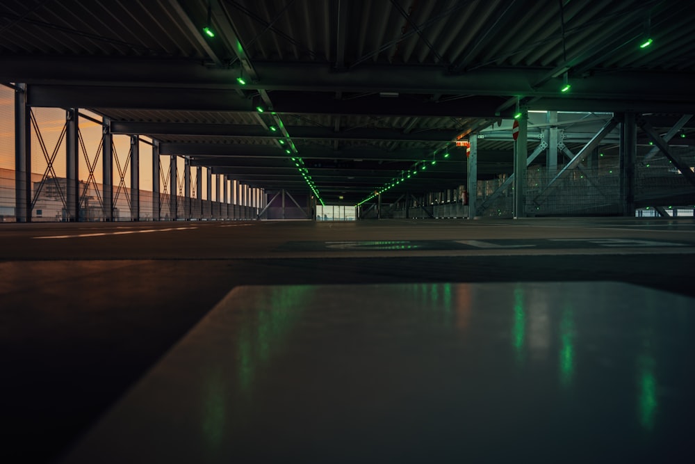 an empty parking garage with green lights at night