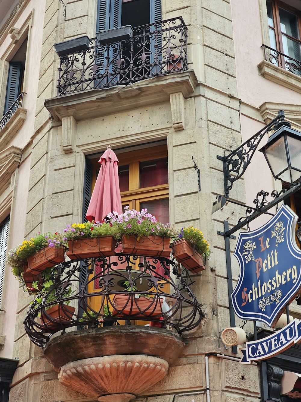 a building with a balcony with a pink umbrella