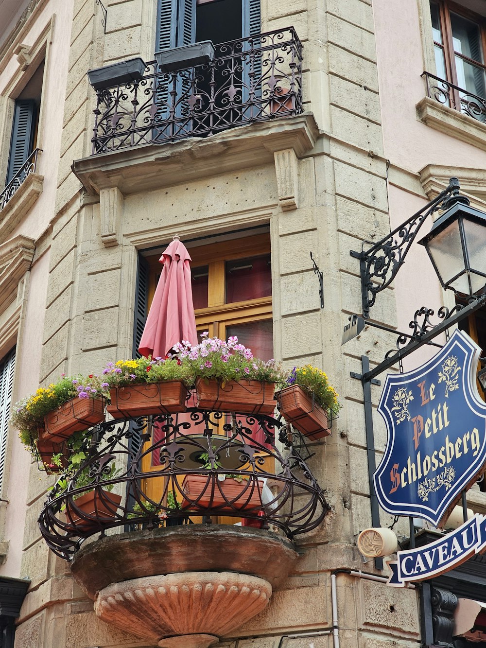 Un edificio con balcón con sombrilla rosa