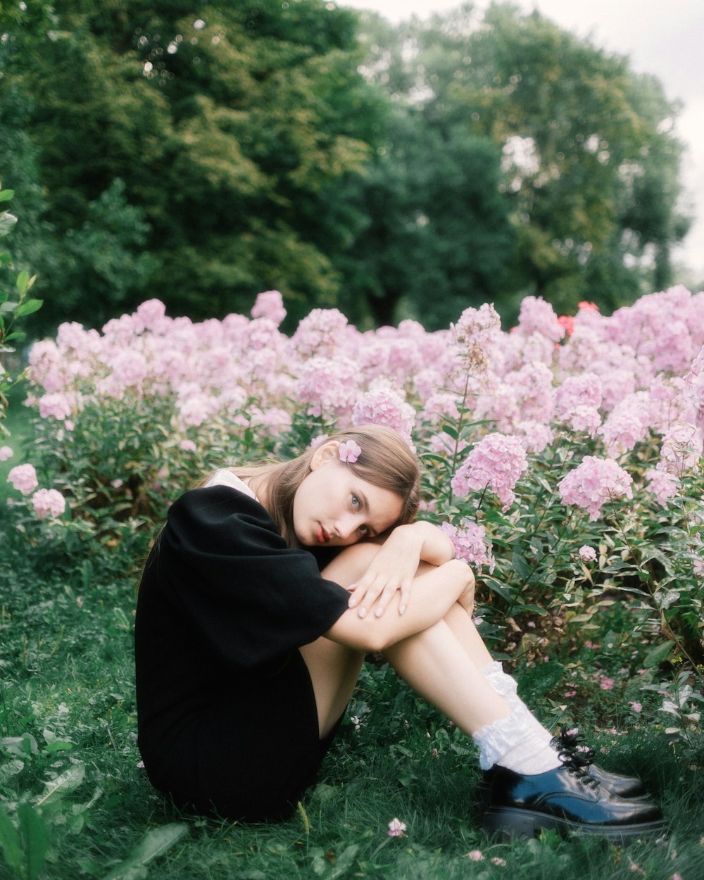 a woman is sitting in a field of flowers