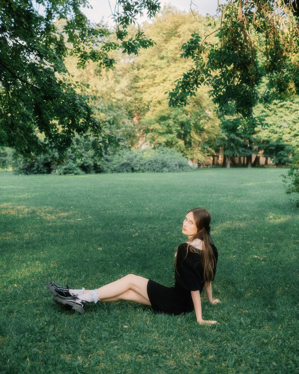 a woman sitting on the grass in a park