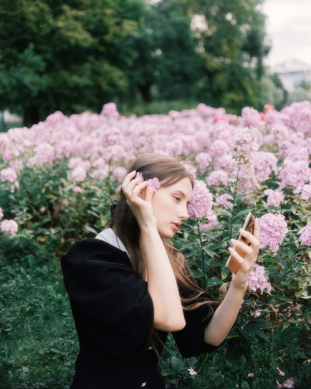 a woman in a field of flowers holding a cell phone