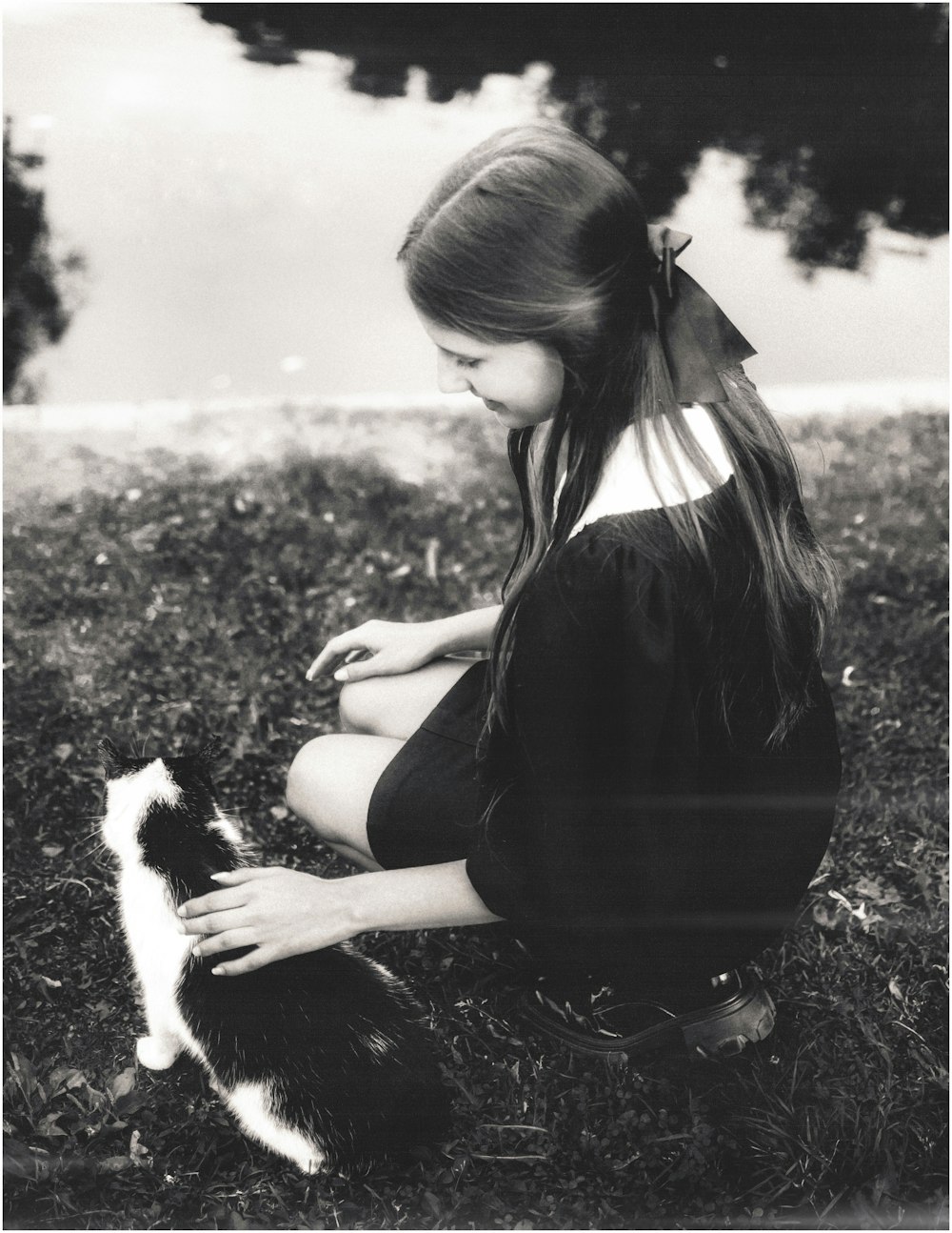 a young girl petting a black and white cat