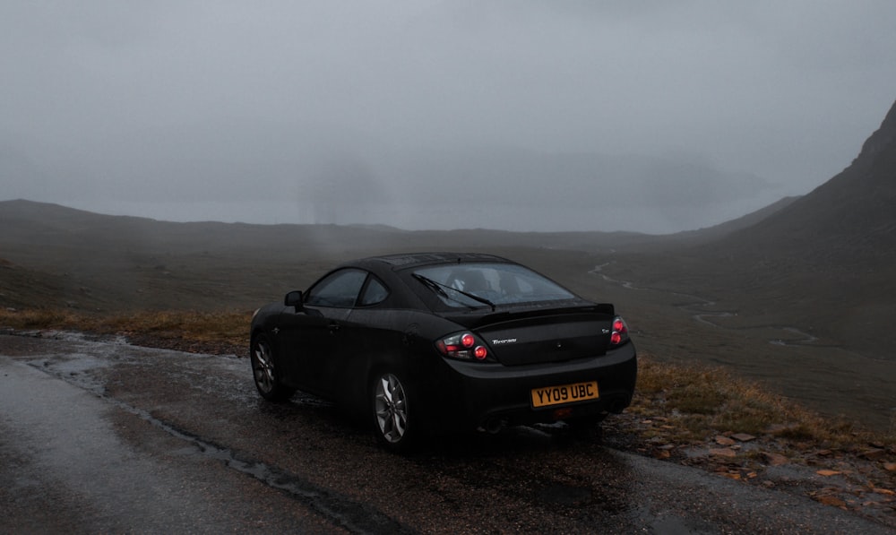 a car parked on the side of a road in the rain