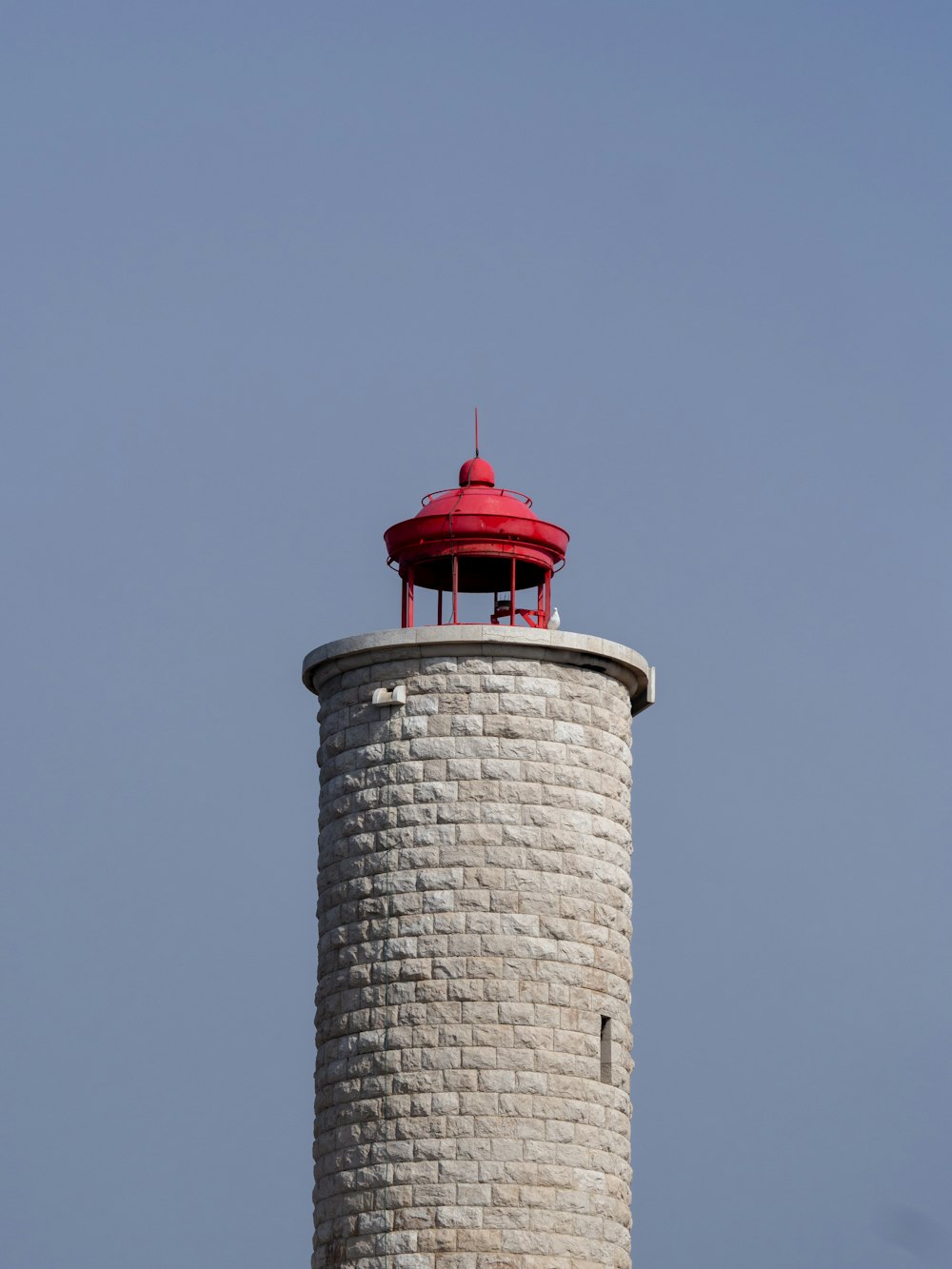 a light house with a red top on a clear day