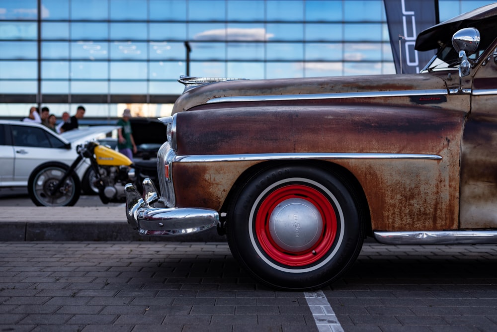 a rusted old car parked in a parking lot