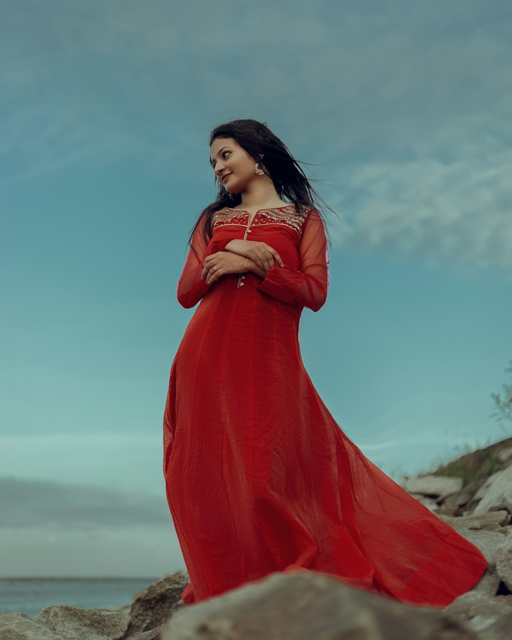 a woman in a red dress standing on rocks