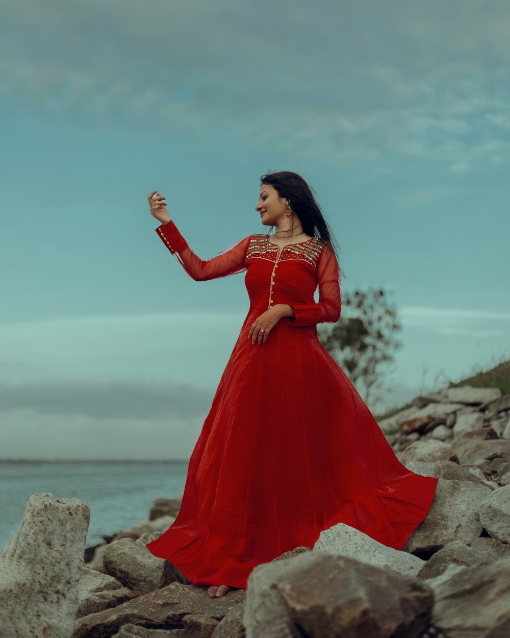 a woman in a red dress standing on rocks