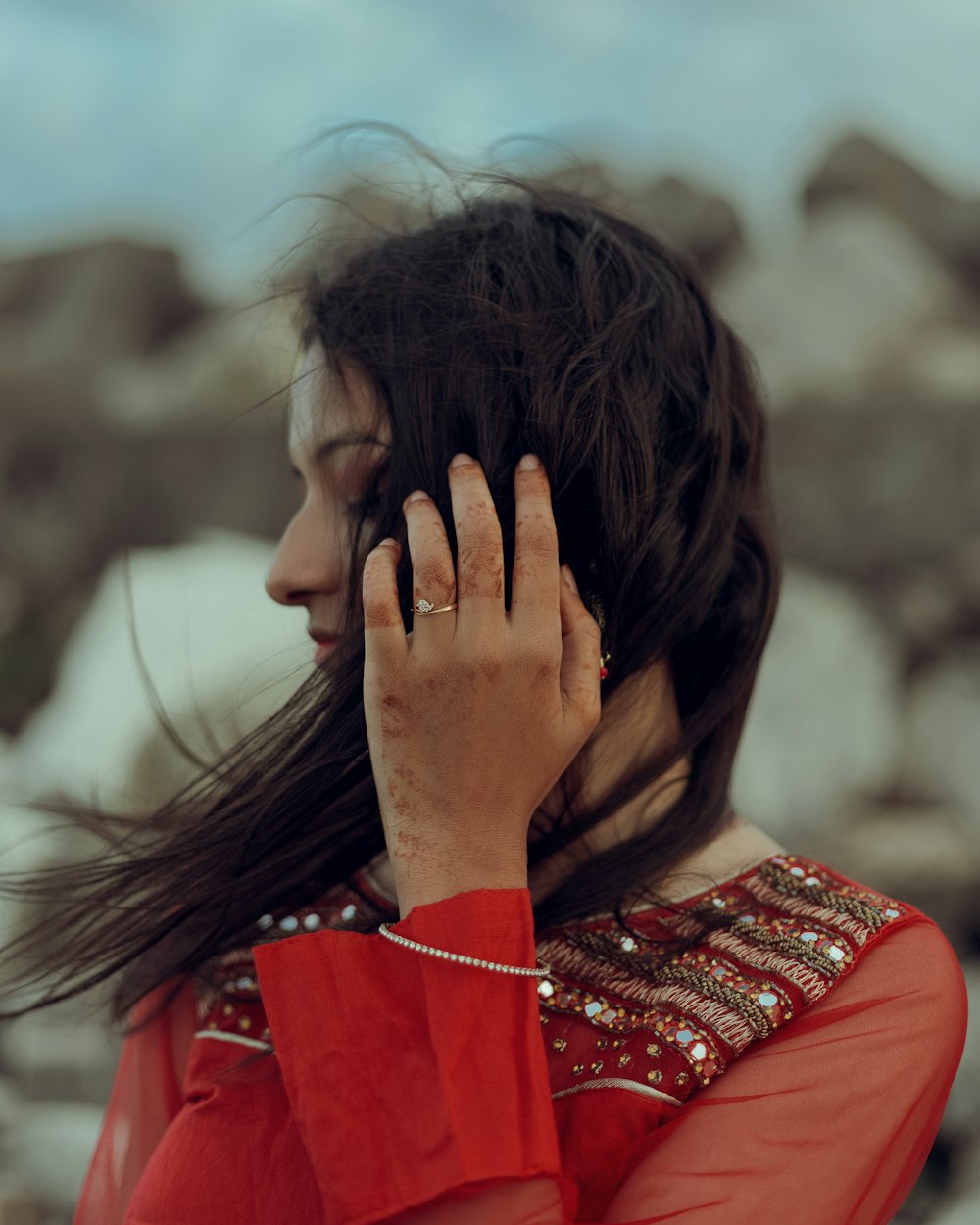 a woman in a red dress holding her hand to her face