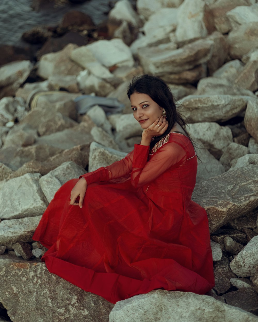 a woman in a red dress sitting on rocks