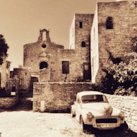 An old postcard featuring a sepia photograph of a quiet village street, bathed in soft afternoon light.