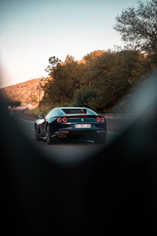 A sleek red sedan taxi cruising along a sunlit highway in Bihar with lush green fields on either side.