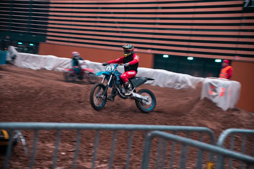 A rider practicing tight turns on a pitbike inside an indoor training facility.