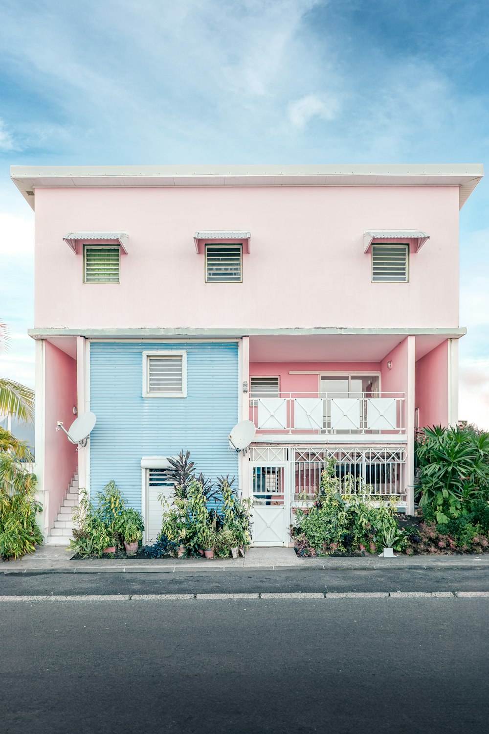 a pink and blue house with a white balcony