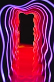 Futuristic light tubes forming an immersive tunnel glowing with gradient colors from purple to teal.