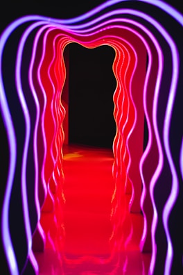 Futuristic light tubes forming an immersive tunnel glowing with gradient colors from purple to teal.