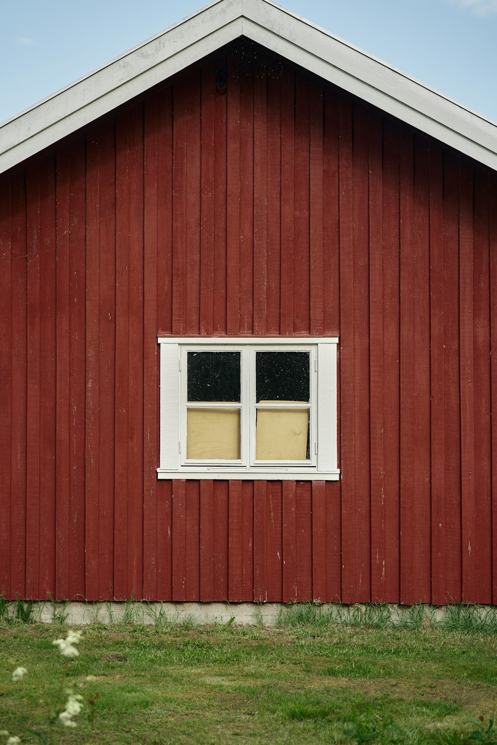 a red building with a white window and grass