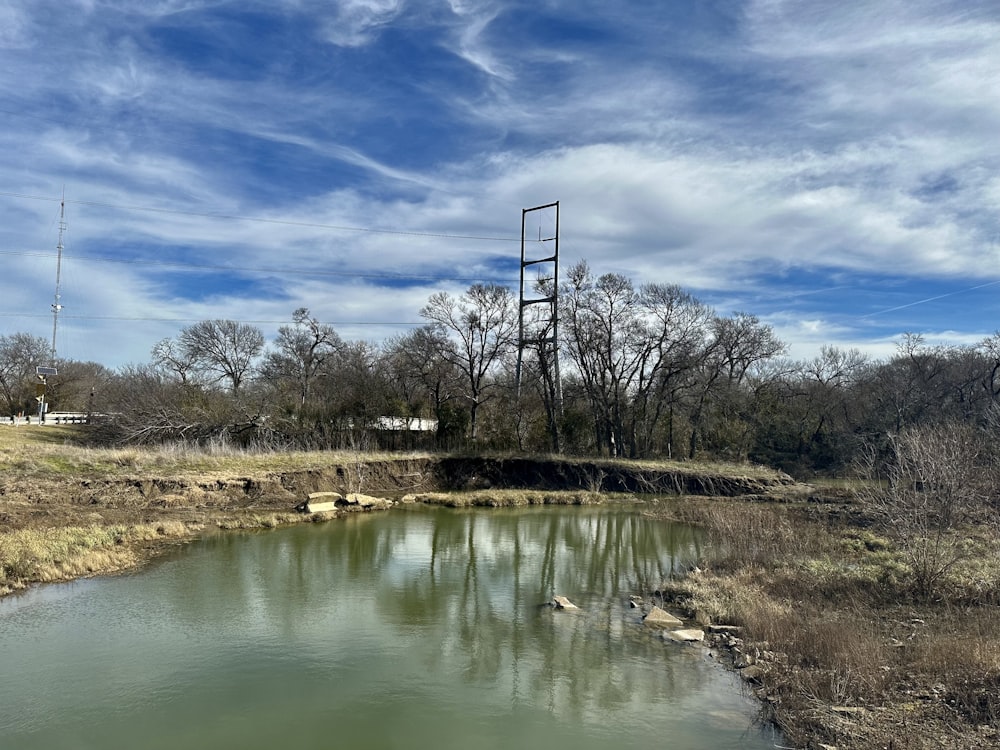 a large body of water sitting next to a dry grass field