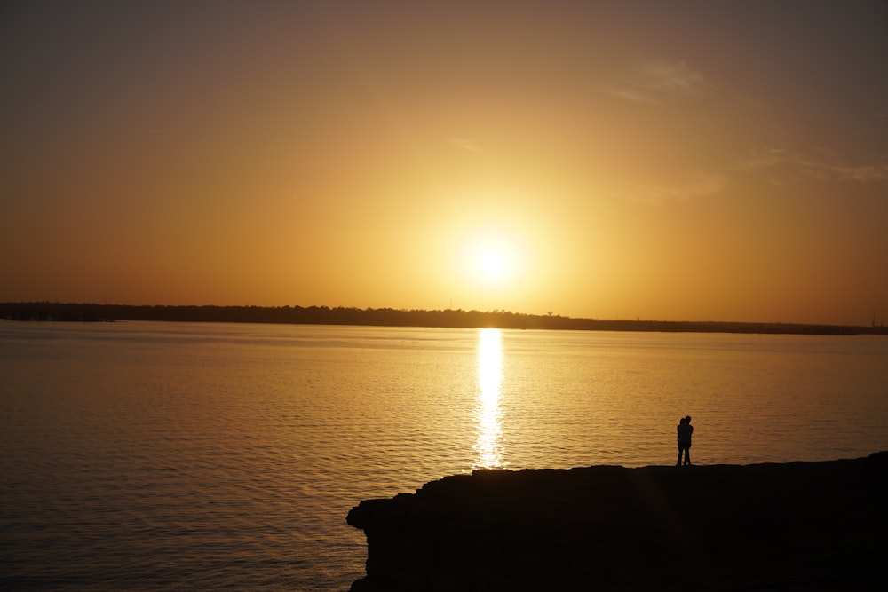 a person standing on the edge of a cliff at sunset